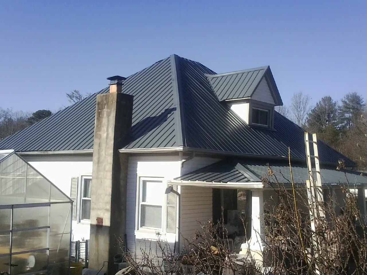 Dark blue standing seam metal roof on a white farmhouse with dormer — Slate & Tile Roof Repair by Roofing Brothers in Columbiana